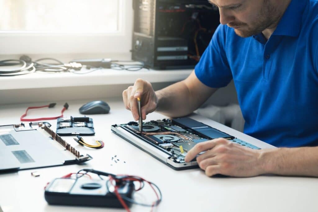 Technician working on disassembled electronics at repair station