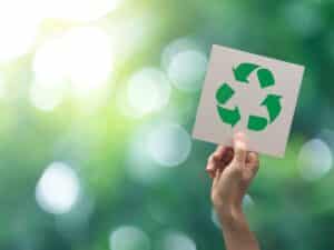 Hand holding recycling symbol against nature backdrop